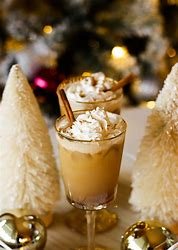 a glass of eggnog with whipped cream and cinnamon sticks